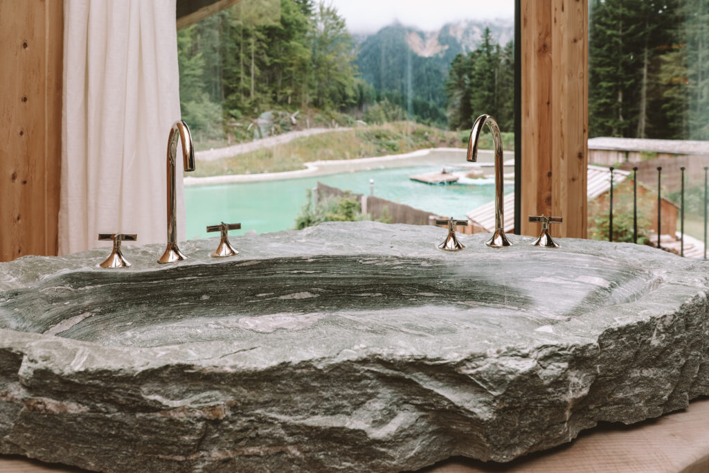 High-end bathroom design with natural stone and wood at Priesteregg Premium ECO Resort